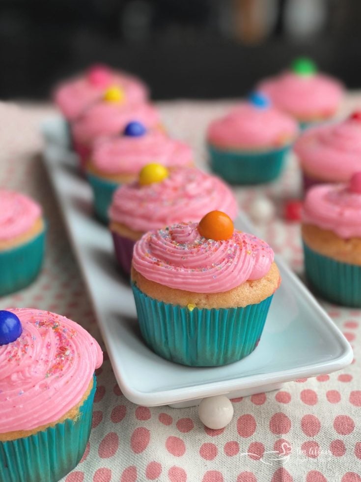 Bubblegum cupcakes on a white platter and on a table