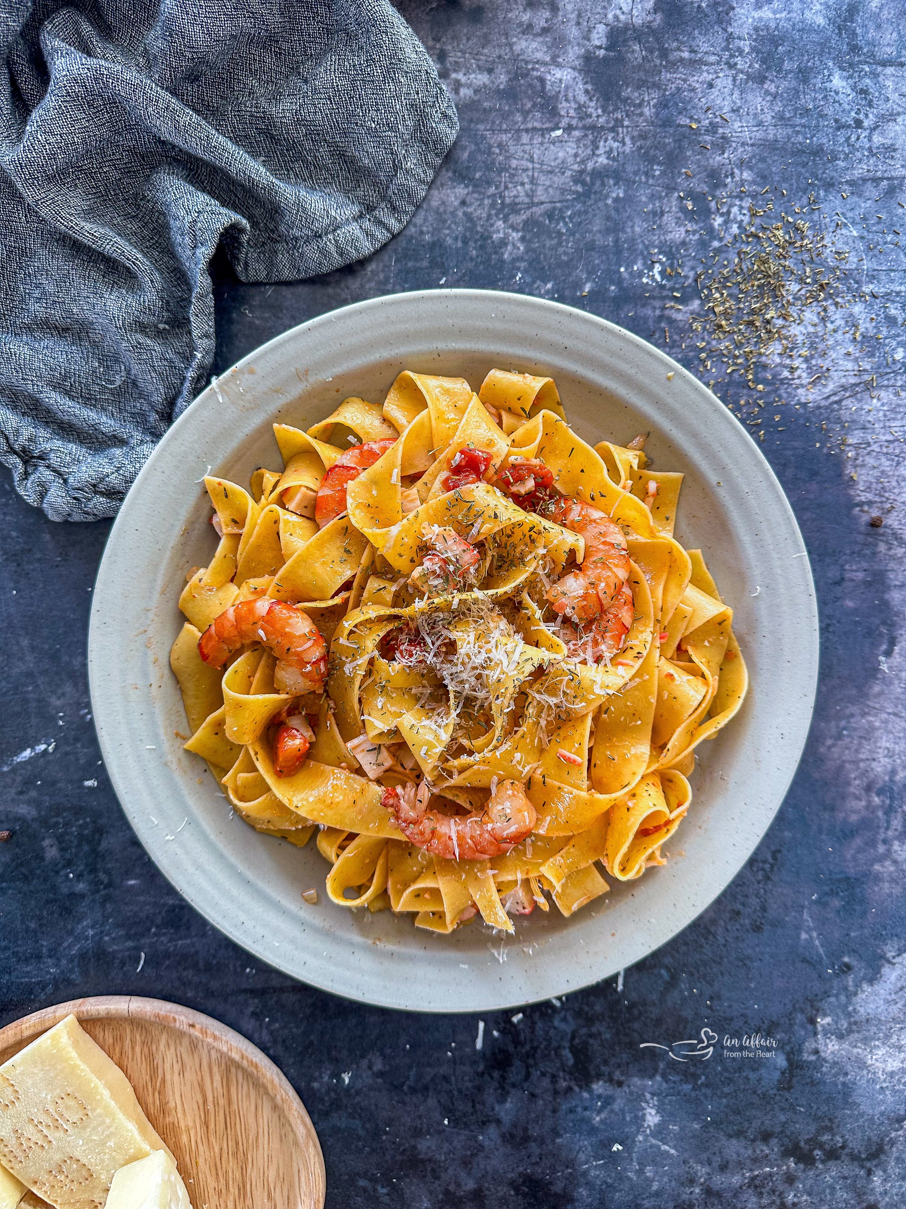 A white bowl of Crab & Shrimp Pasta with shredded cheese on top.