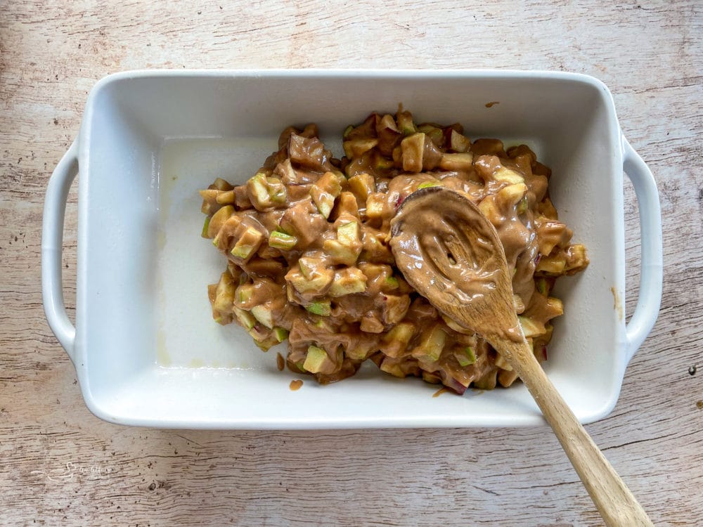 apple mixture being placed into dish with wooden spoon