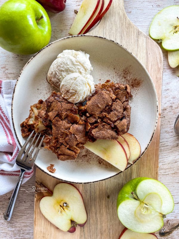 top view of fresh apple cake with apple slices and ice cream in white bowl