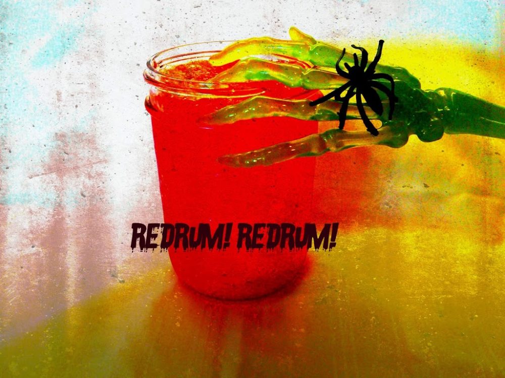 Side view of redrum punch in a glass with a fake skeleton hand on it. Text "redrum! redrum!"