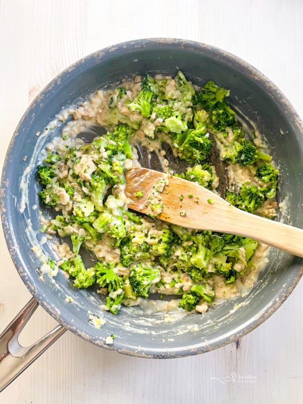 adding broccoli and flour to pan with mushrooms and onion 