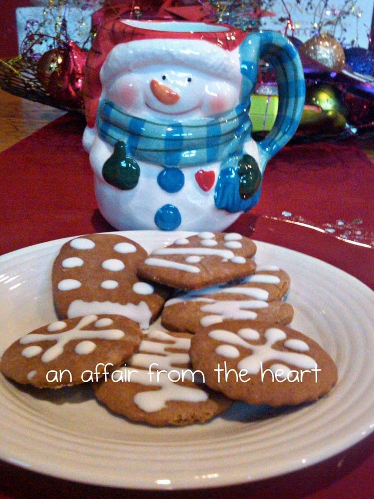 close up of Karen’s Ginger Bread Cookies on a white plate and a snowman mug on a red surface