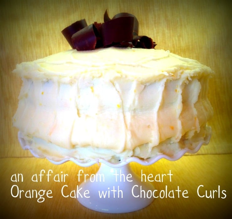 Side view of Orange Layer cake onn a white cake platter with text "orange cake with chocolate curls"