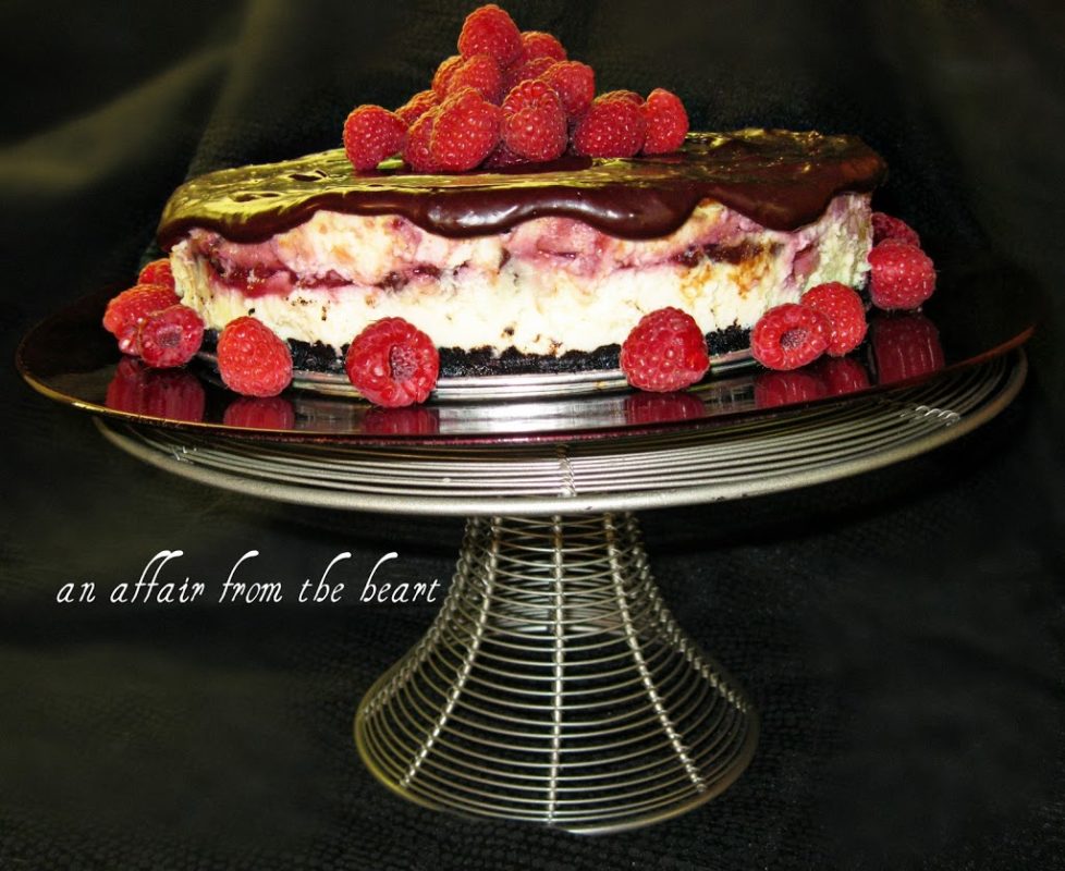 White Side view of Chocolate Raspberry Truffle Cheesecake on a cake stand