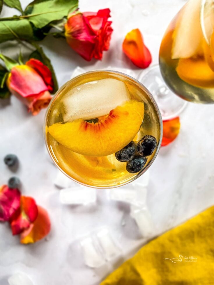 Overhead of rose sangria topped with slices of peach and blueberries.