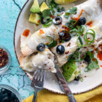 Two enchiladas on plate with fork and knife