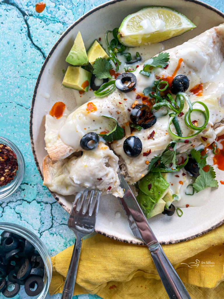 Two enchiladas on plate with fork and knife