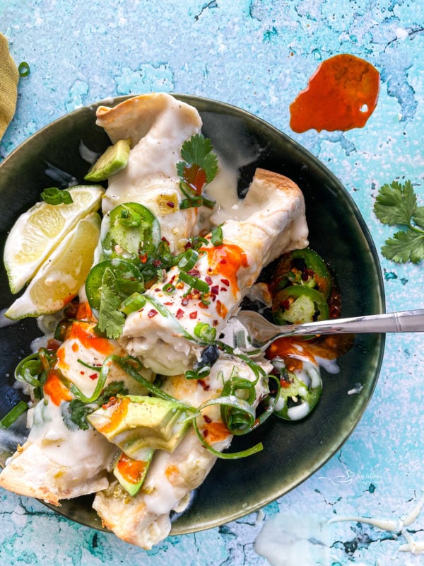 Enchiladas on plate with fork and garnishments