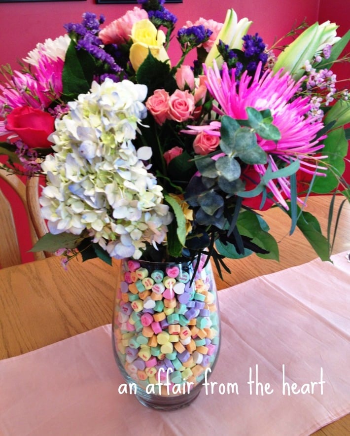 Glass Vase filled with Conversation Hearts and then flowers added to make a beautiful centerpiece.