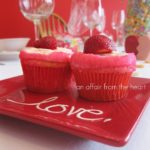 Side view of 2 Strawberry daiquiri cupcakes on a red plate that ahs the word love on it