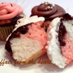 Neapolitan Cupcakes and one cut in half on a white surface