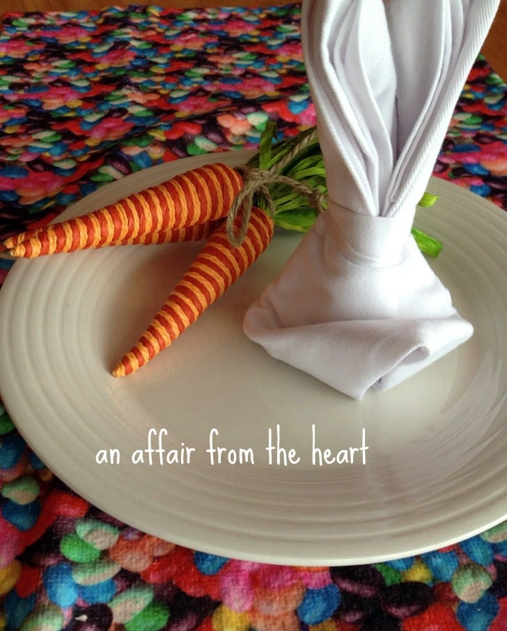 a white bunny napkin and fake carrots on a white plate