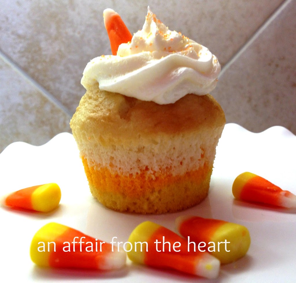 close up of a candy corn cupcake and candy pieces on a white plate