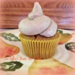 Side view of a single pumpkin cupcake with cinnamon buttercream frosting on a multicolored plate.