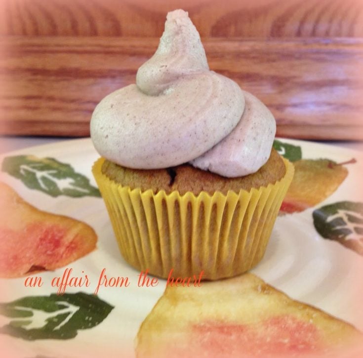 Side view of a single pumpkin cupcake with cinnamon buttercream frosting on a multicolored plate.