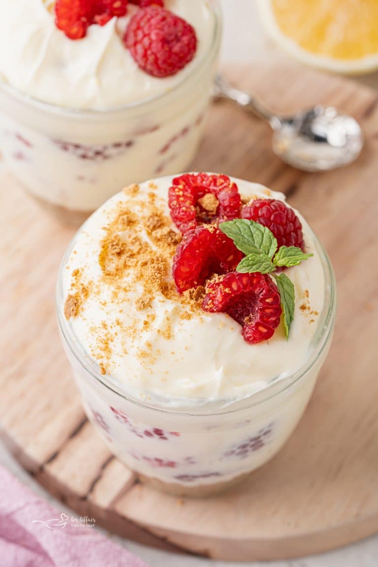 No Bake Lemon Raspberry Cheesecakes topped with fresh raspberries, graham cracker crumbs and a sprig of mint.