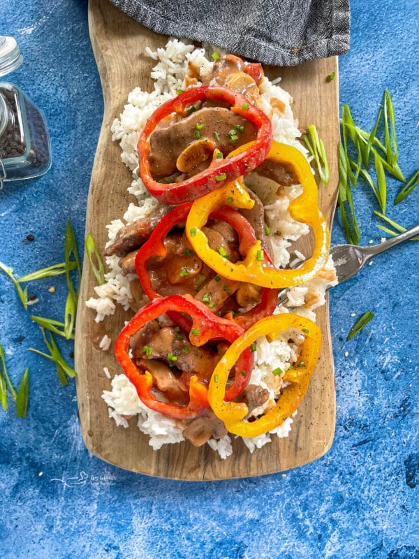 Steak, rice, and peppers on wooden surface