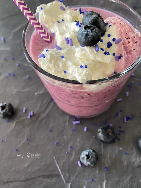 Top view of purple cow smoothie with whipped cream and berries