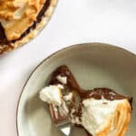 Slice of chocolate meringue pie and a fork on a cream colored plate.