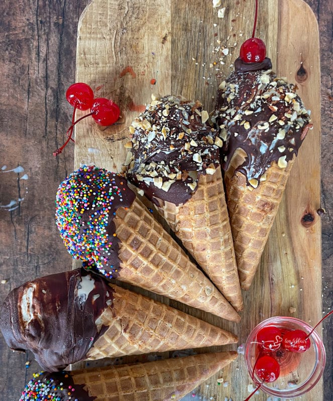 four chocolate dipped cones with nuts and cherries