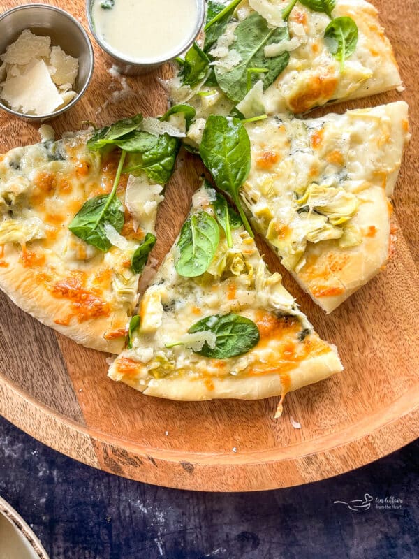 cutting and serving spinach and alfredo pizza