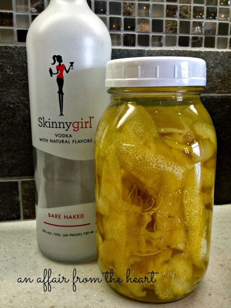 Lemon rinds and vodka in a sealed jar with a bottle of skinny girl vodka next to it