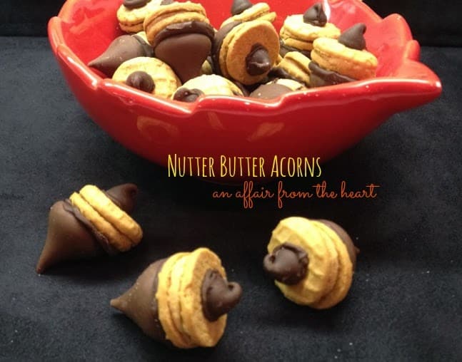 Nutter butter acorns in a red leaf bowl and on a black surface with text "Nutter butter acorns"