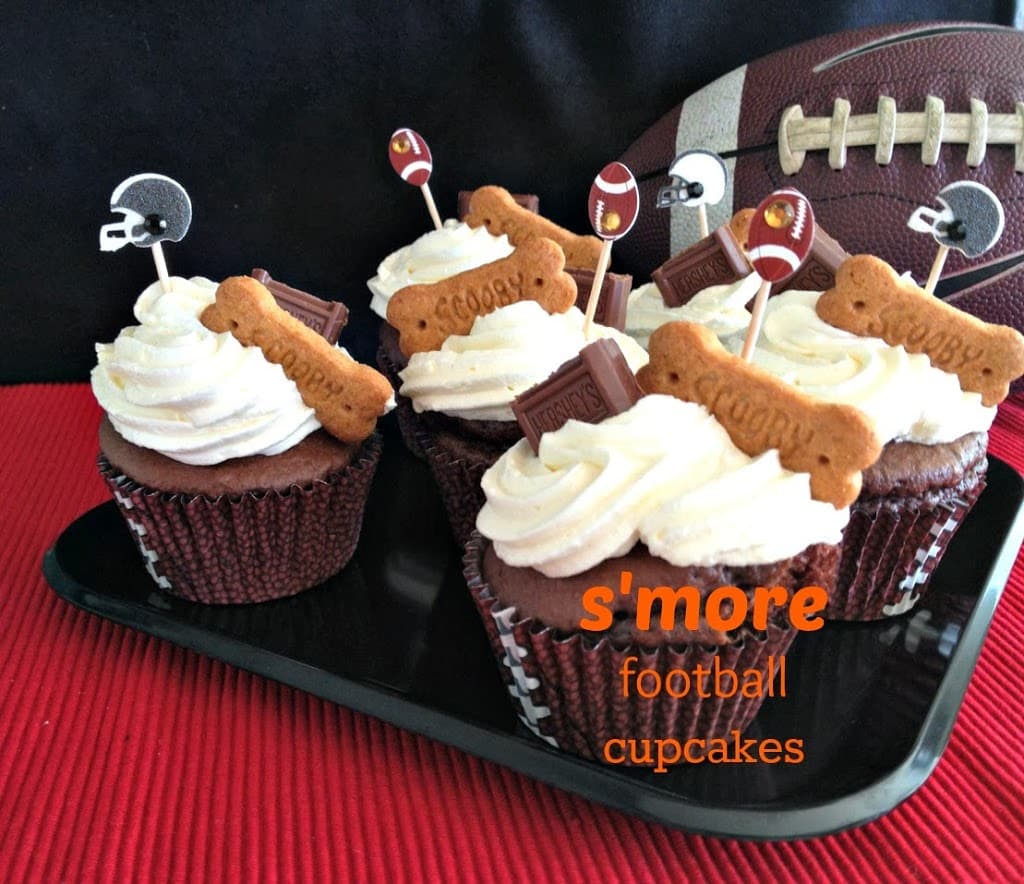 side view of s'more cupcakes on a black tray with text "s'more football cupcakes"