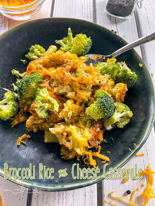 Front view of broccoli and cheese casserole on dark plate with spoon