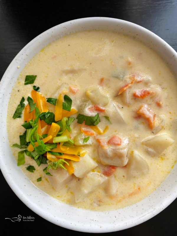 Top view of cheesy potato soup in white bowl