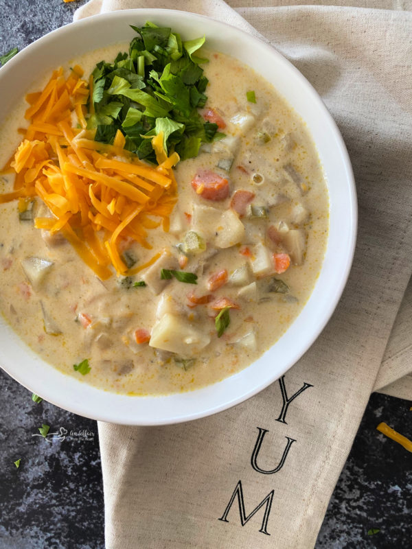 Top view of cheesy potato soup in white bowl with cheese and parsley on top