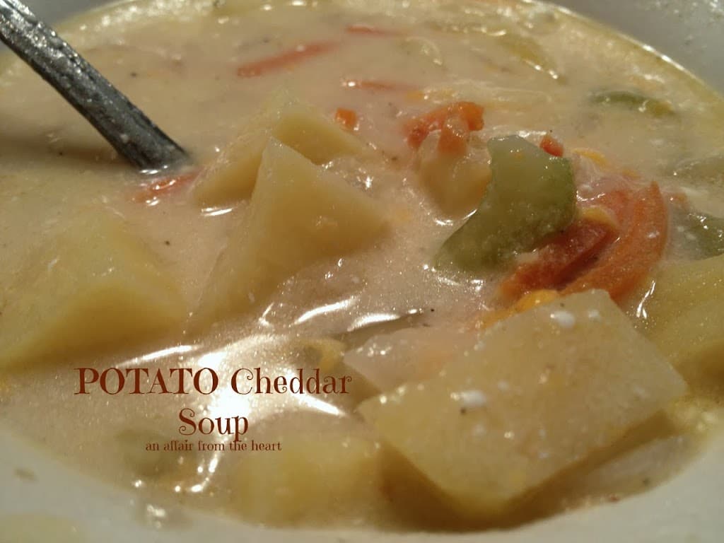 Close view of potato cheese soup in bowl with spoon