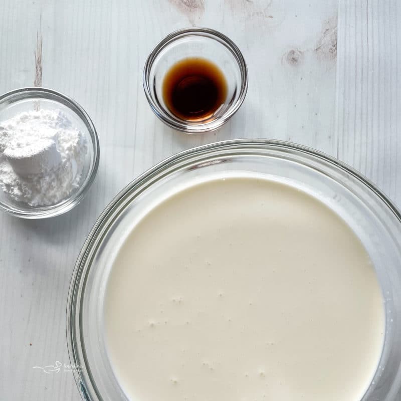 top view of heavy cream in bowl with sugar and vanilla