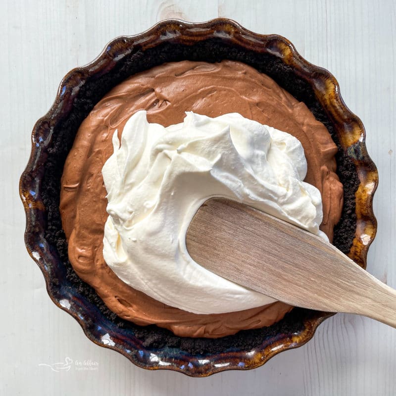 spreading whipped topping on top of chocolate pie