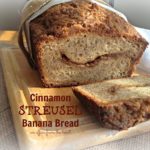 Cinnamon Streusel banana bread on a wood cutting board with the end cut off. Text "Cinnamon streusel banana bread"