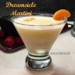 Dreamsicle martini in a martini glass garnished with an orange slice on a white surface. Text "dreamsicle martini"