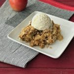 The Very BEST Apple Crisp topped with ice cream on a white plate