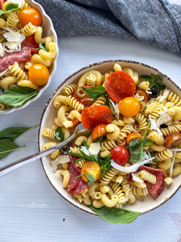 Two bowls of pasta salad with tomatoes and pepperoni