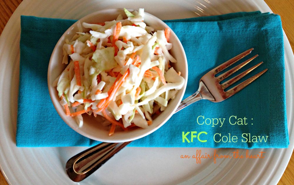 Overhead of KFC ColeSlaw in a white bowl and a fork on a blue cloth napkin with text "copy cat: KFC Cole Slaw"