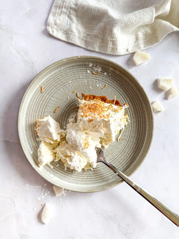 Homemade Coconut Cream Pie on a grey plate with a fork
