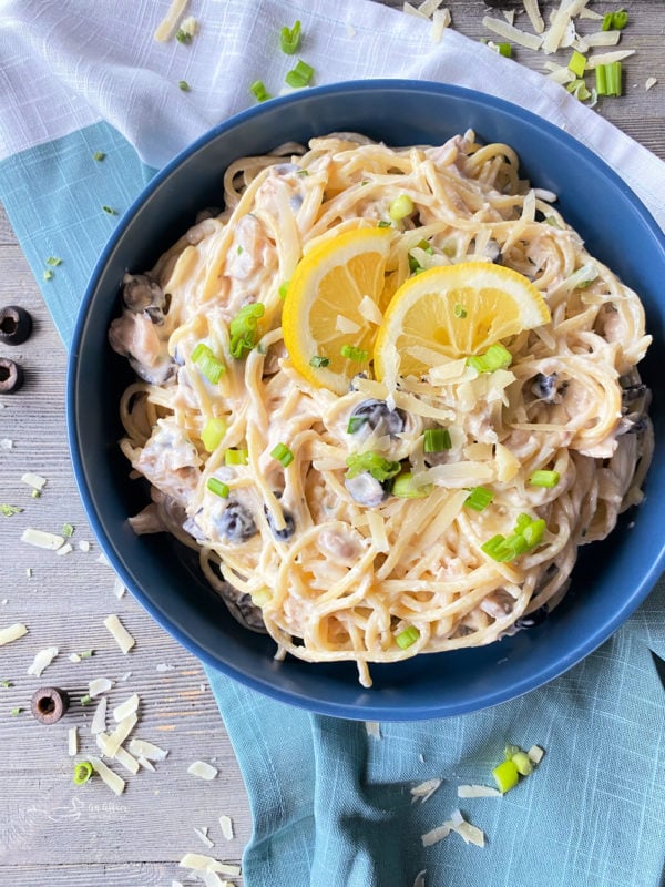 top view of tuna spaghetti in bowl with lemon wedges