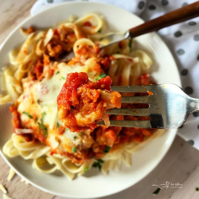 close view of chicken parmesan on fork over plate