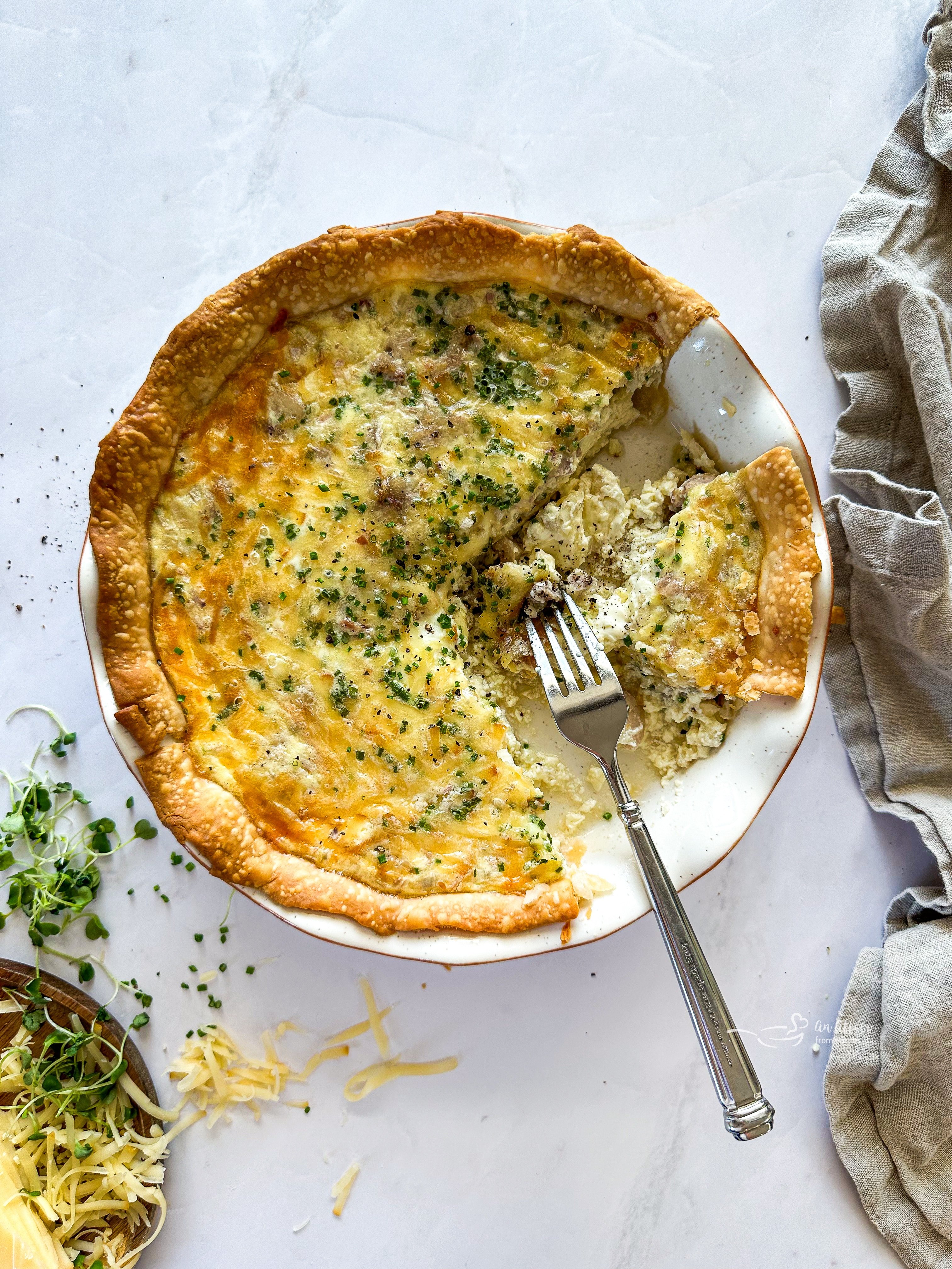 Ham and Smoked Gouda Quiche with pieces missing and a fork taking a piece.