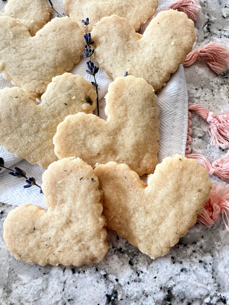 heart shaped lavender shortbread stacked on a white cloth.