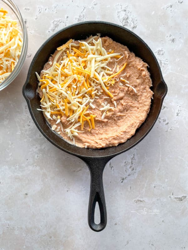 adding cheese on top of the bean dip