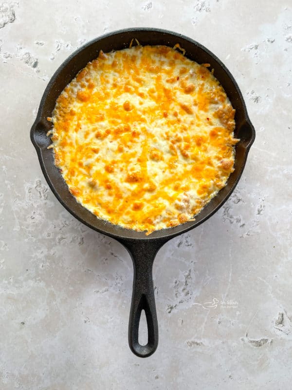 a hot skillet full of bean dip with melted cheese on top