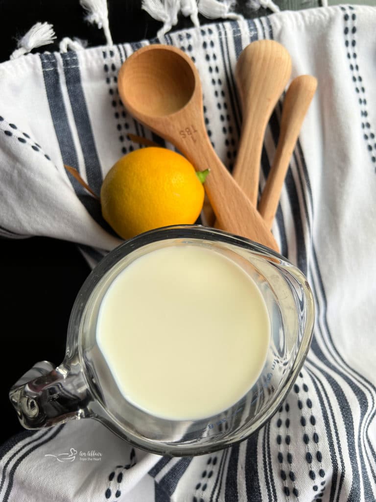 Buttermilk Substitute image with milk and lemon and measuring spoons