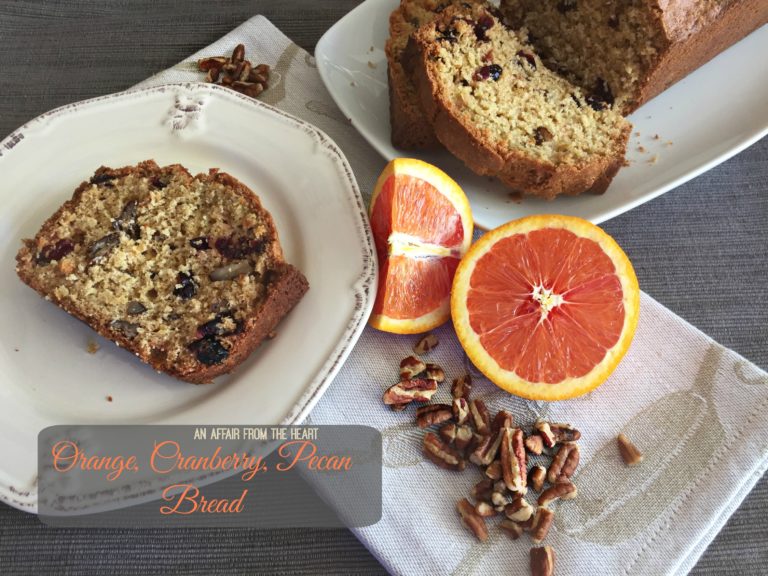 Overhead of a slice of bread on a white plate with text "Orange Cranberry Pecan Bread"