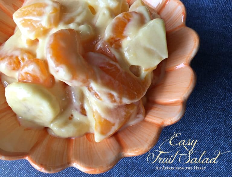 Close up of fruit salad in a coral serving bowl with text "easy fruit salad"